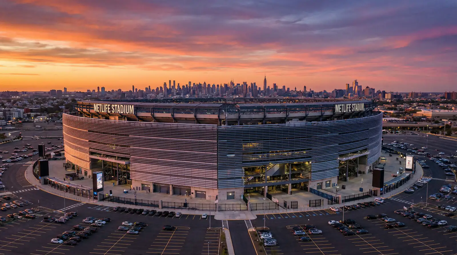 MetLife Stadium exterior at sunset with the New York skyline visible in the background